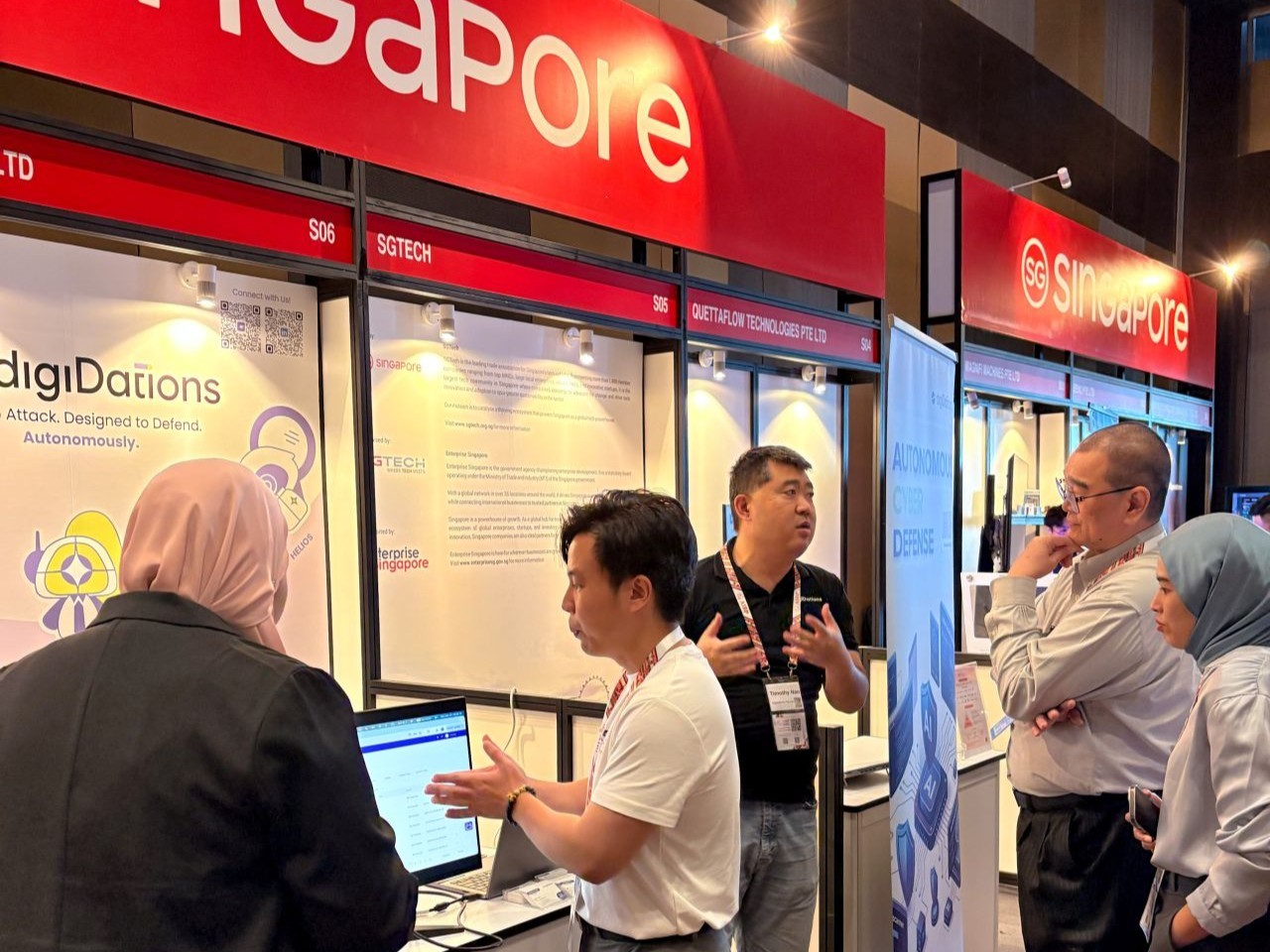 Attendees gathered around a laptop demo at the digiDations booth at AIBP 2026 in Kuala Lumpur