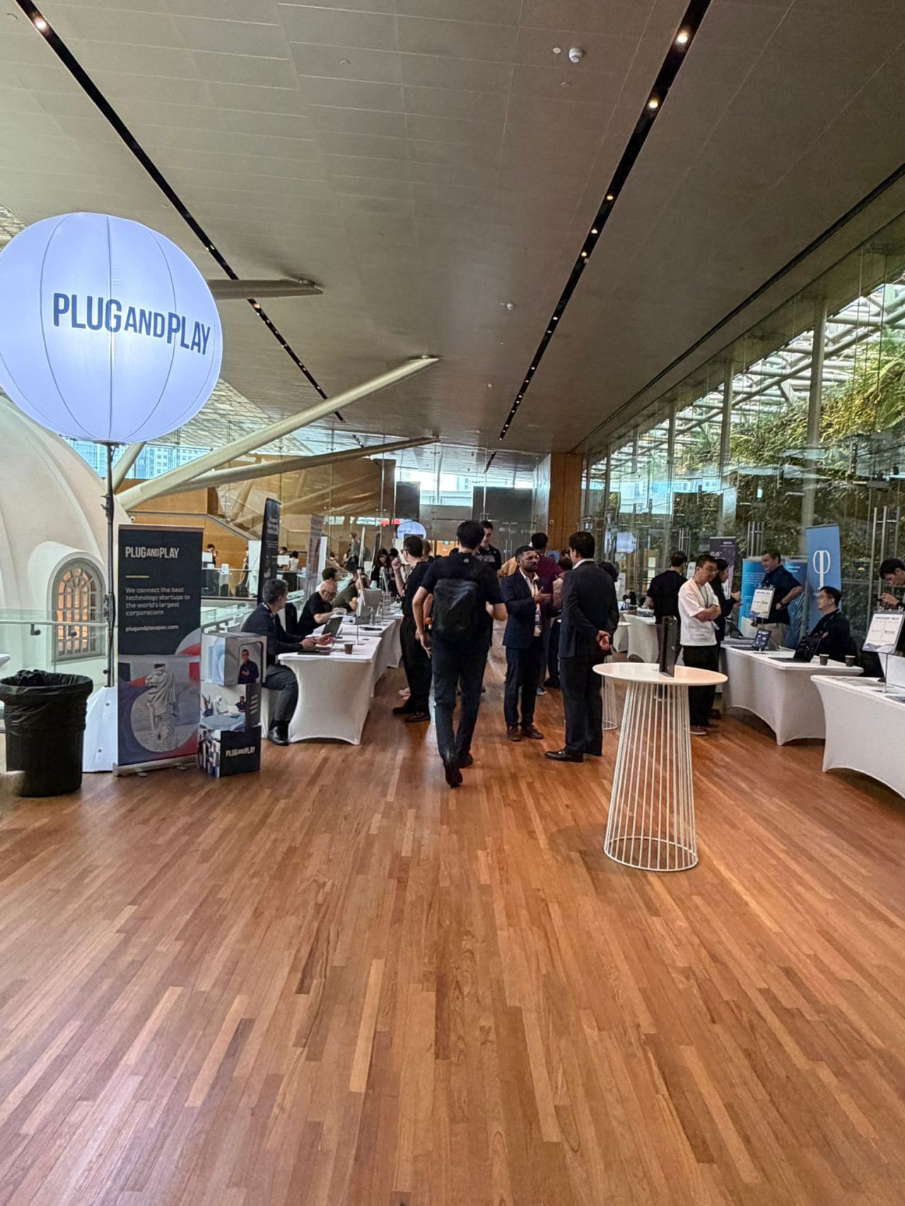 Plug and Play APAC 2025 exhibition hall with branded balloon and exhibitor tables